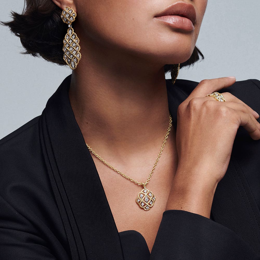 A white with gold trim salad bowl filled with a green salad on a white tabletop.